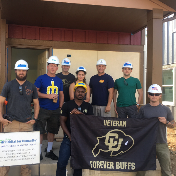 Students posing in front of a home under construction.