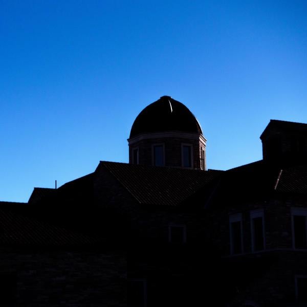 Silhouette of a building on campus in front of a bluebird sky