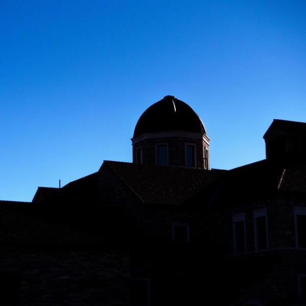 Silhouette of a building on campus in front of a bluebird sky