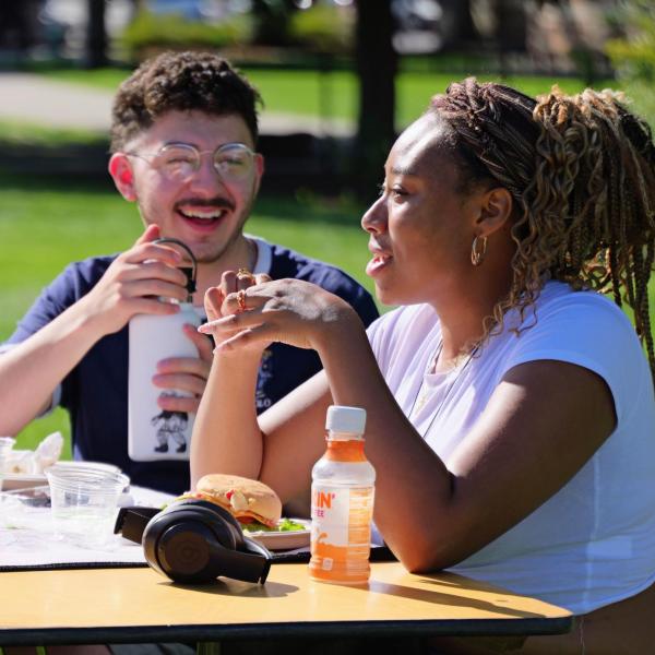 two campus community member sit at an outdoor table together