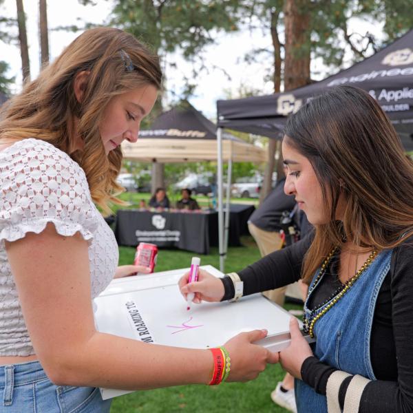 Graduate signing a graduation book during Grad Bash