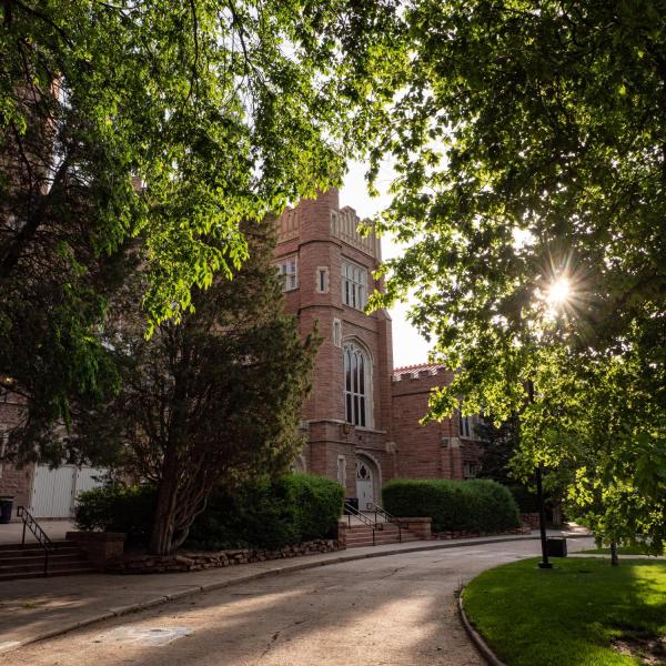 Sun filters through the trees in early morning by Macky Auditorium