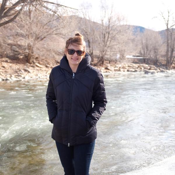 Elizabeth Koebele stands in her winter coat with the Arkansas River in the background.