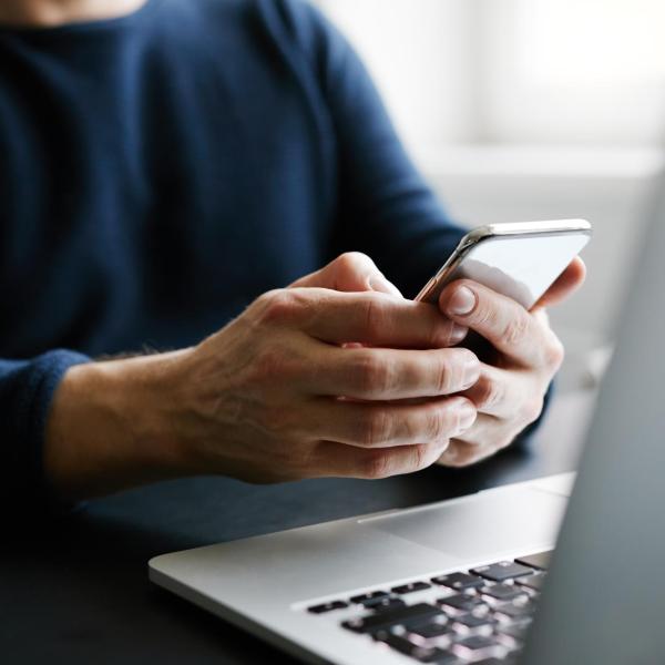 person checking phone and sitting near laptop