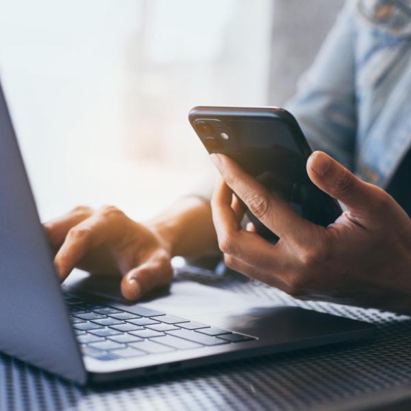 person checking mobile phone and laptop