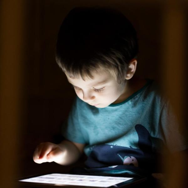 Little boy using tablet device at nighttime