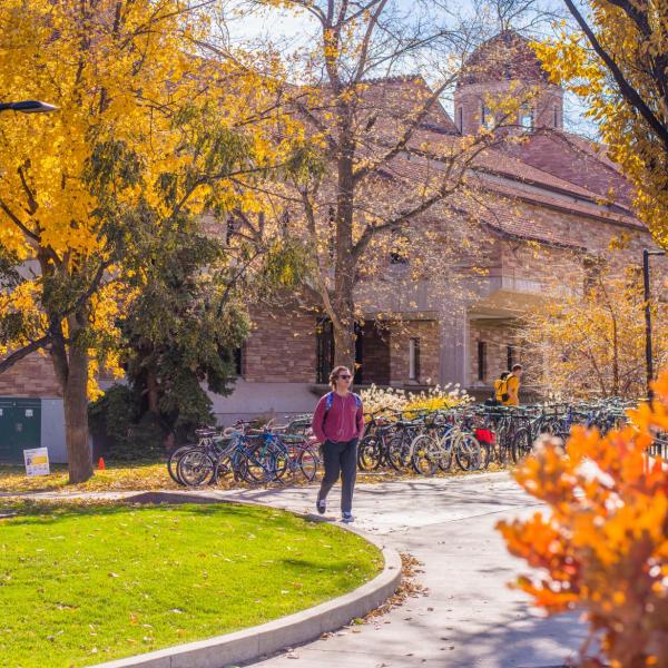 Student walks on campus with fall colors