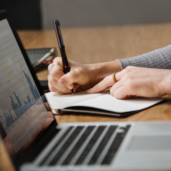 Person works on a budget with notepad and laptop