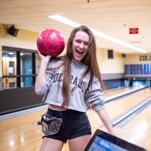 A student poses with a bowling ball at The Connection on campus