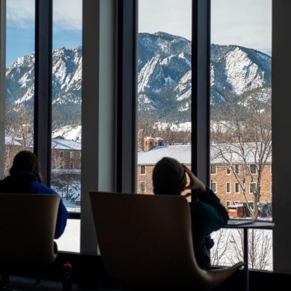 People sit in lounge chairs inside a campus building.