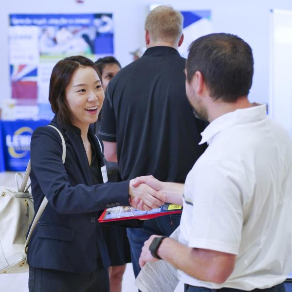 student shakes hand with employer at a career fair on campus
