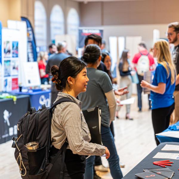 Students visit employer booths at a career fair on campus