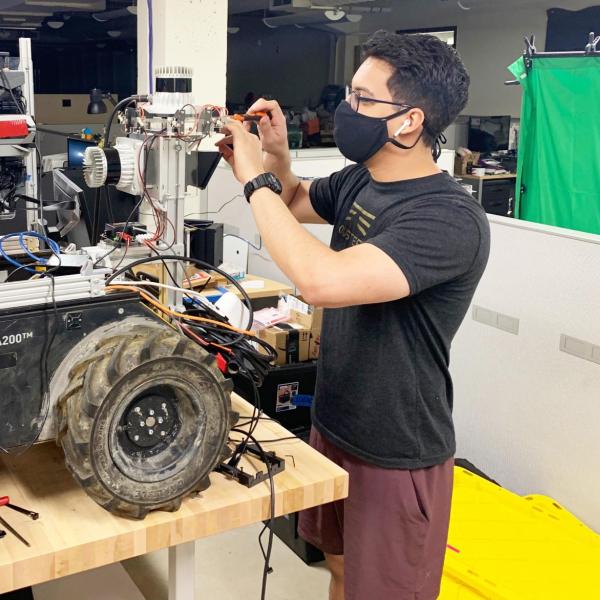 A member of a robotics research team working in a lab after a return to on-campus research