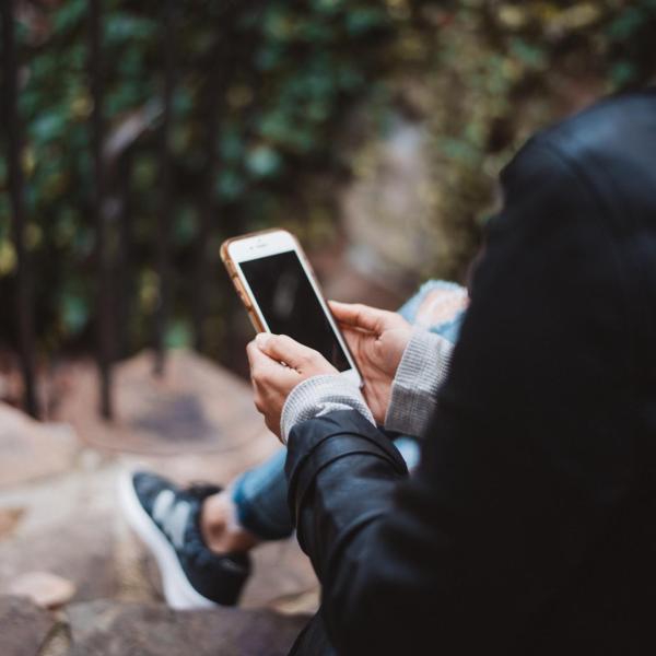 Person sitting on steps outside holding a phone