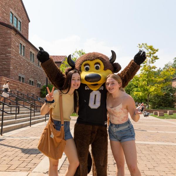 Two roommates pose for a photo with Chip the buffalo mascot
