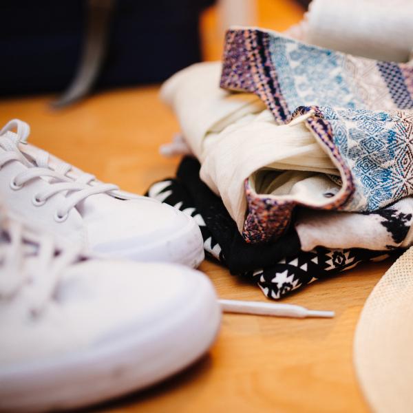 white sneakers, folded shirts and straw fedora hat on table