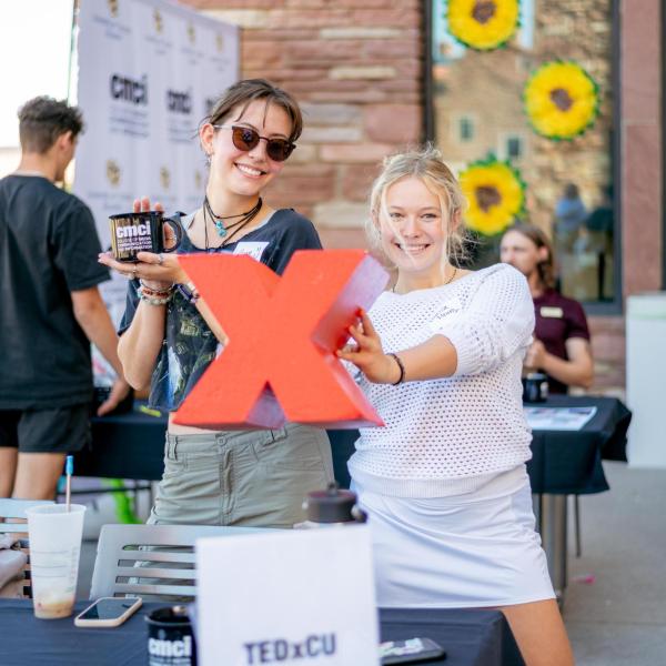 Students hold up a red X, of the TEDx logo, at an involvement fair booth
