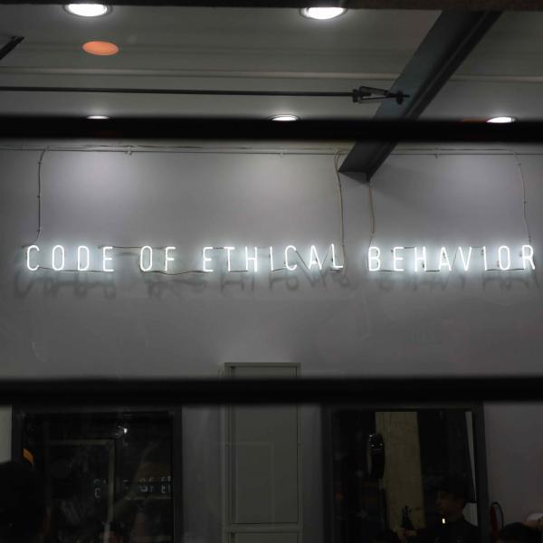 A stock image of a neon sign that says "Code of Ethical Behavior"