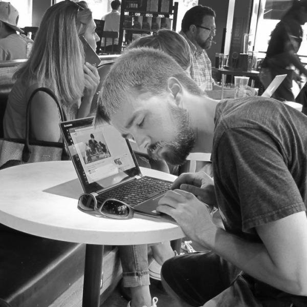 A person endeavors to hear the soundtrack of a video in a busy coffee shop