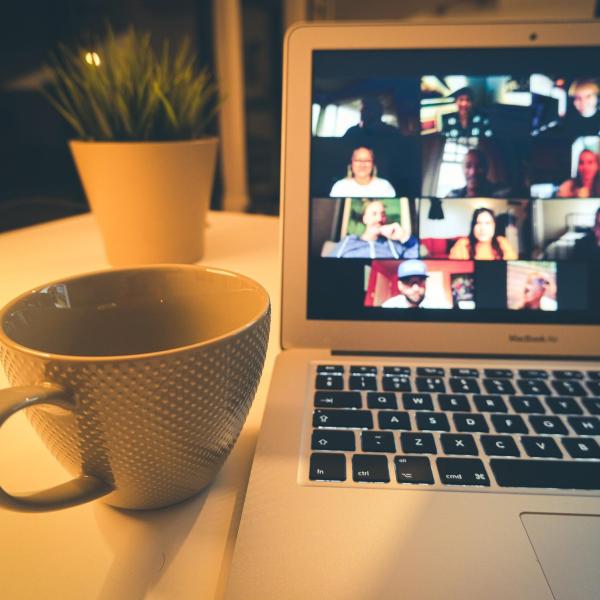 Zoom webinar on a laptop next to a cup of coffee