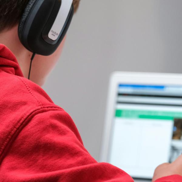boy wearing headphones and doing school work on a laptop