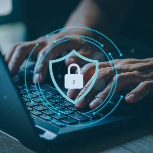 person on laptop with security lock and shield graphic overlay