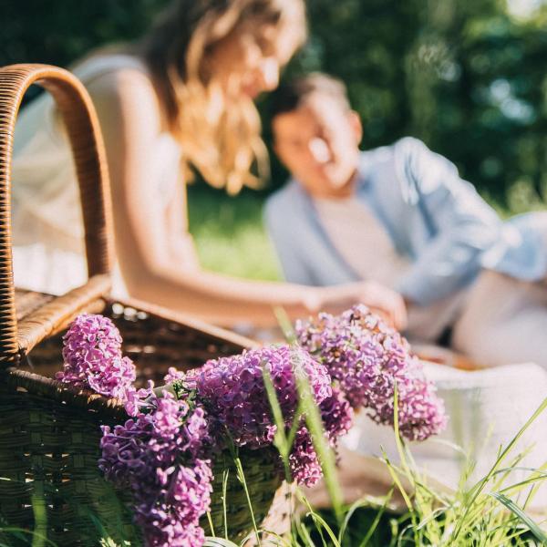 Couple sitting on a blanket with purple lilac flowers.