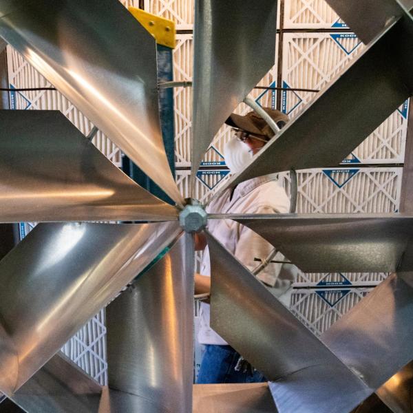 Maintenance worker viewed through a ventilation fan.