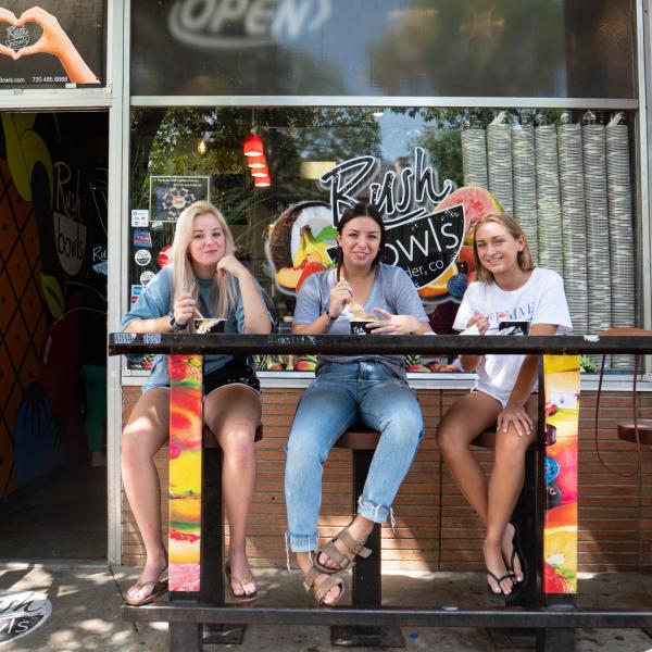 Students sit outside of Rush Bowls on The Hill