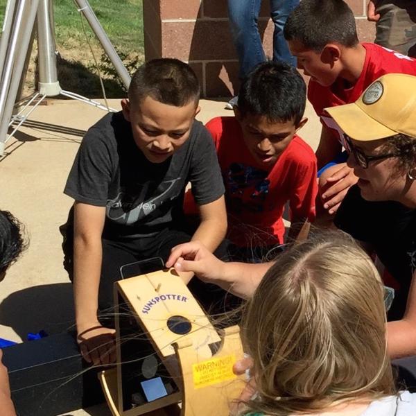 CU Boulder astronomy and physics student Sam Strabala searches for sunspots with middle schoolers in Keenesburg, Colorado as part of a science outreach program.