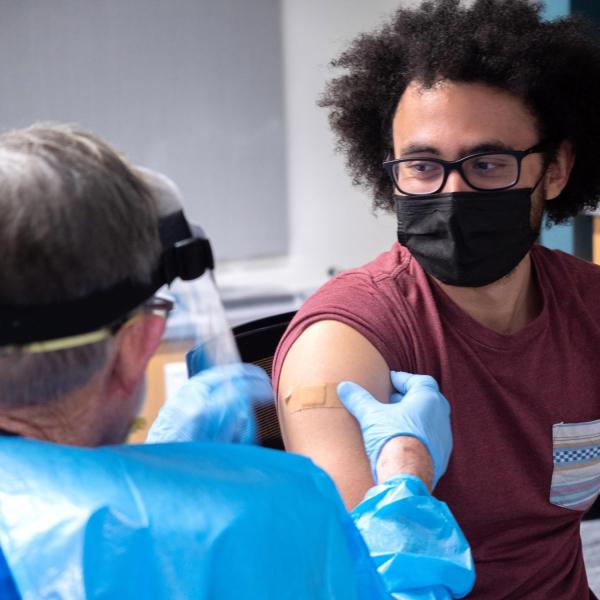 Richard Biggs, 20, an evolutionary biology major at CU Boulder, gets his first dose of the Moderna vaccine from Dr. Laird Wolfe. (Photo by Glenn Asakawa/University of Colorado)