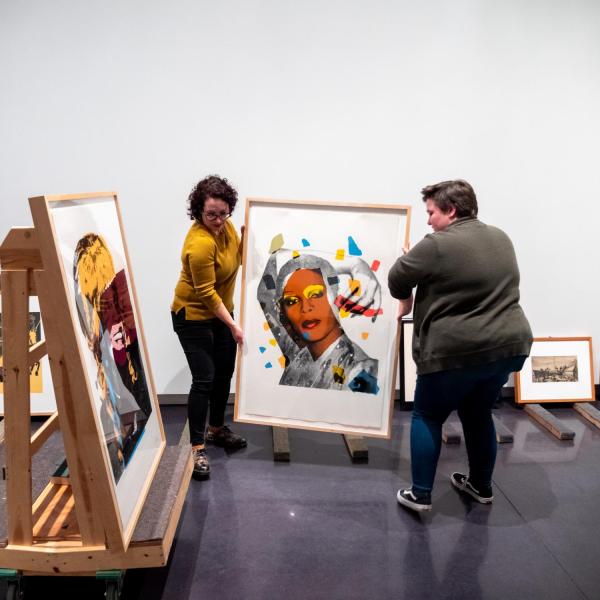 Students move artwork at the CU Art Museum's new exhibition, Persuasive Prints.
