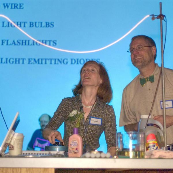 Two faculty members present a electrical light-based experiment.