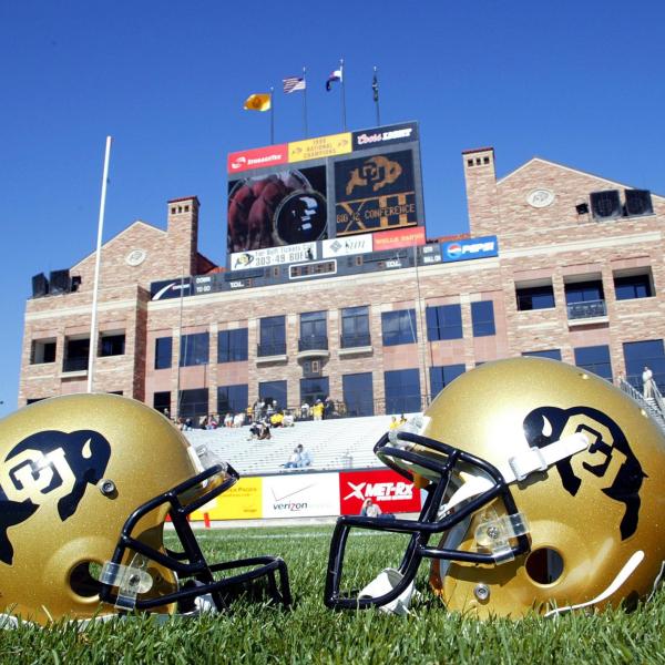 Two helmets are seen on the football field with the Dal Ward building in the background.