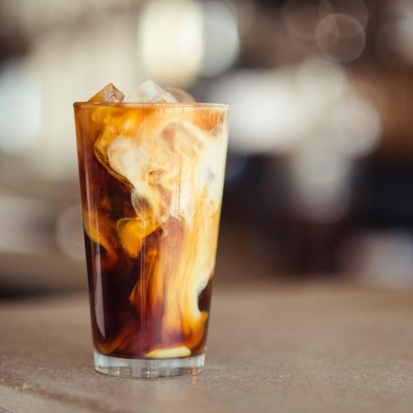 Cream swirls around a glass of iced coffee