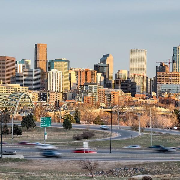 Denver's skyline. The foreground shows cars driving on a highway.