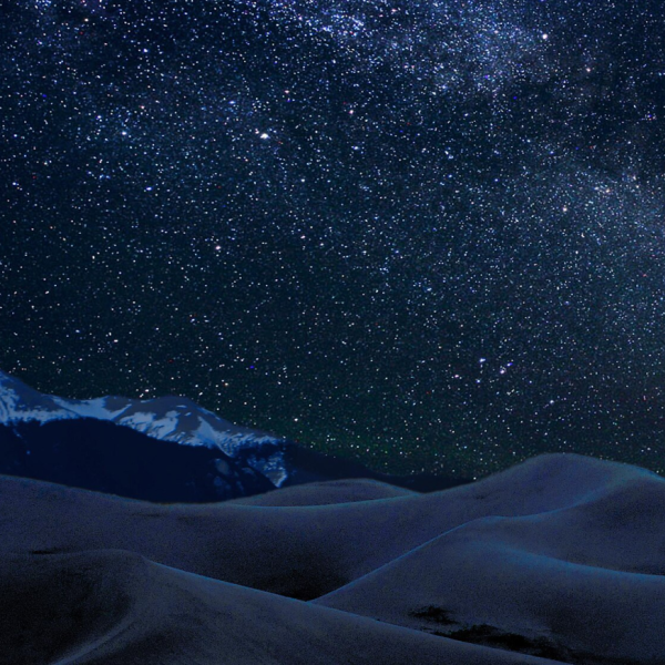 Stars in the night sky above sand dunes