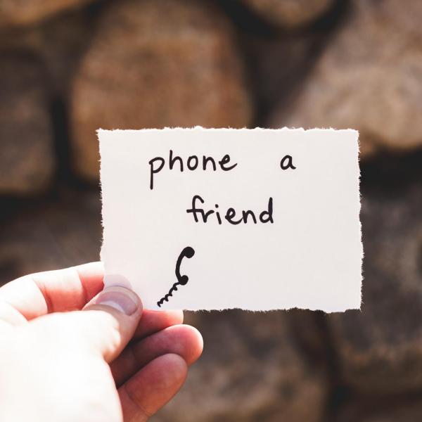 Stock image of a person holding a note saying "Phone a friend"
