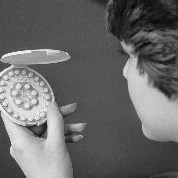 black and white photo of woman holding birth control pills