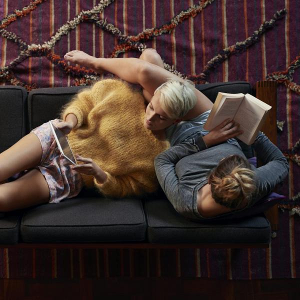 LGBTQ+ couple lying on a couch and reading