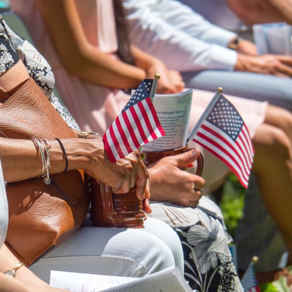 People sitting at an event holding small American flags