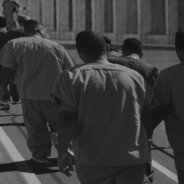 A black and white illustration showing black men in prison uniforms