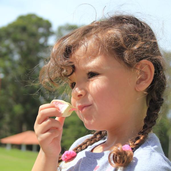 A girl eats a marshmallow.