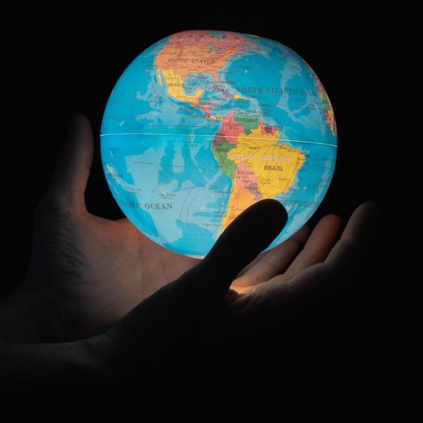 Two hands hold a globe, lit from inside. (Photo by Greg Rosenke/Unsplash)
