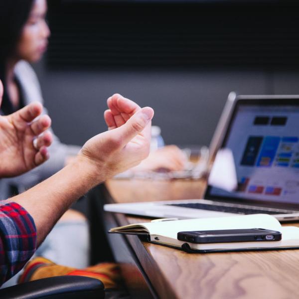 Employees sit at a conference table with laptops