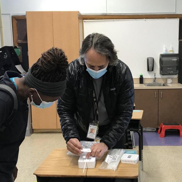 Professor Mark Hernandez demonstrates the installation process for the classroom air quality remote sensors to CU Boulder student volunteer technicians Christiane Nitcheu and Sylvia Akol. (Photos courtesy Anna Segur)