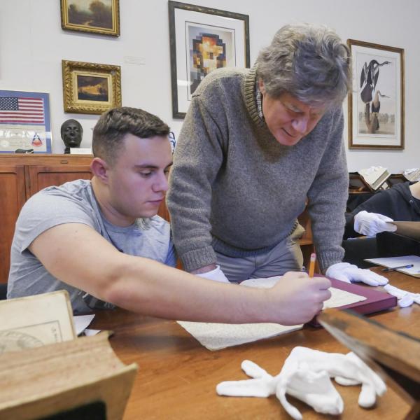 Professor works with student analyzing archives