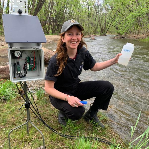 researcher collecting water from a stream
