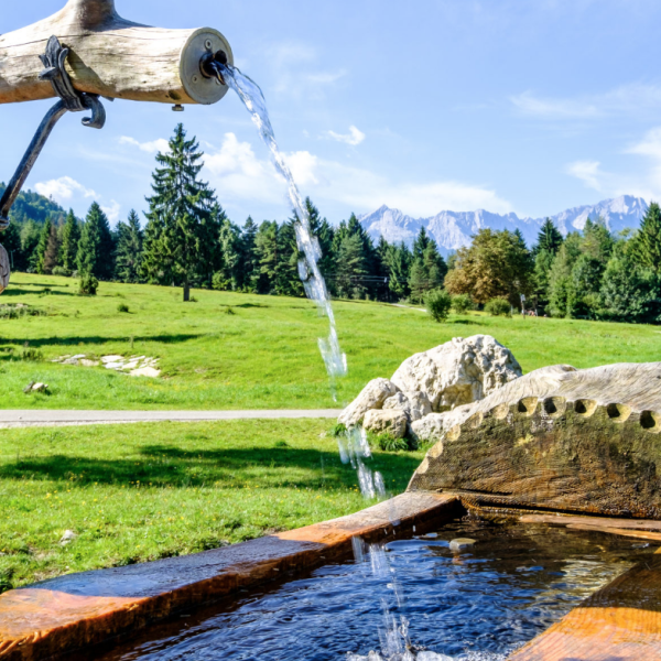 A water spout in nature, with mountains in the background