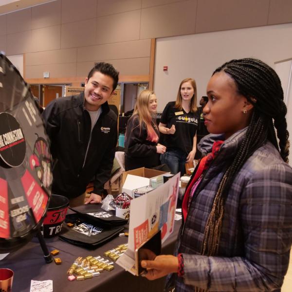 Student spins a prize wheel at The Connection booth at the spring Involvement Fair